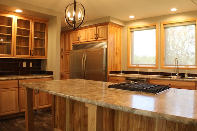 kitchen with stainless steel built in refrigerator, decorative light fixtures, a notable chandelier, sink, and decorative backsplash