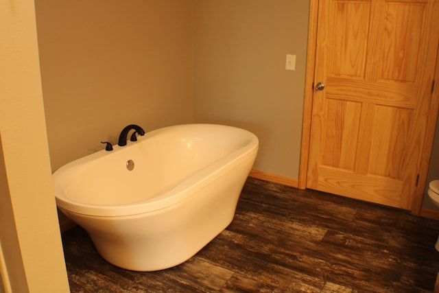 bathroom with wood-type flooring, a bathing tub, and toilet