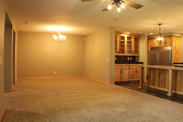 unfurnished living room with ceiling fan with notable chandelier, dark carpet, and a textured ceiling