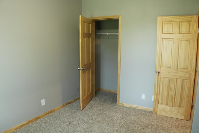 unfurnished bedroom featuring a closet and light colored carpet