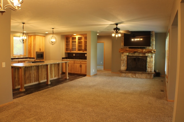 unfurnished living room with a fireplace, ceiling fan, and dark carpet