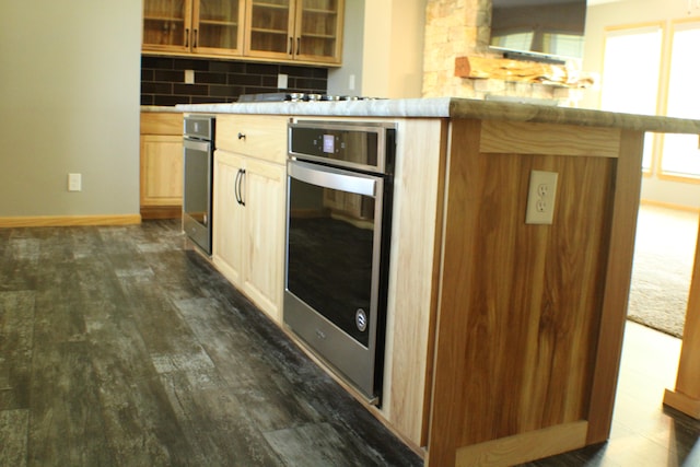 kitchen featuring dark wood-type flooring, kitchen peninsula, stainless steel oven, light brown cabinetry, and backsplash