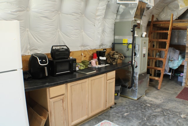 kitchen featuring light brown cabinetry, heating unit, white fridge, and concrete floors