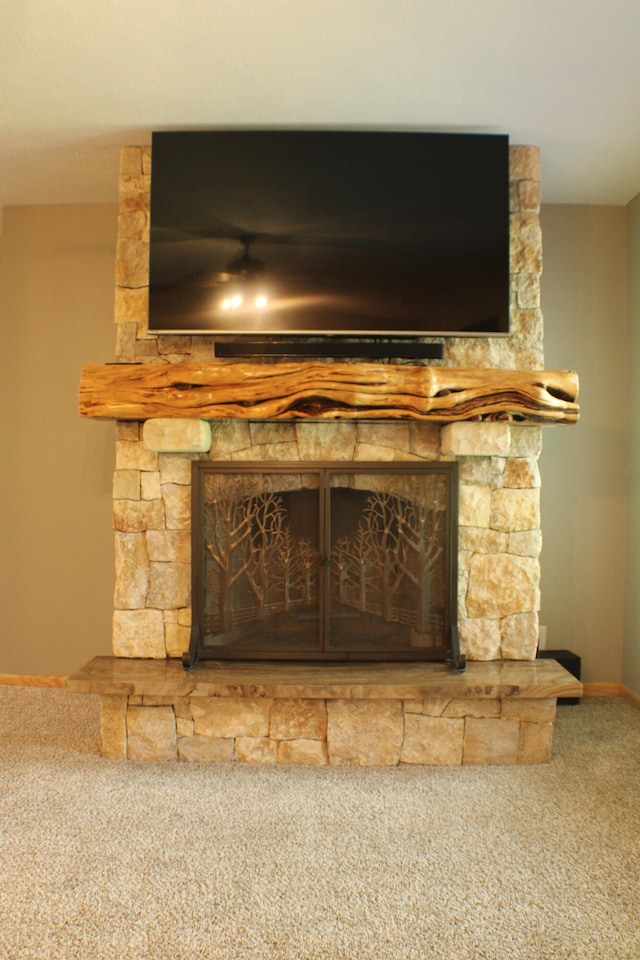 interior details with carpet floors and a stone fireplace