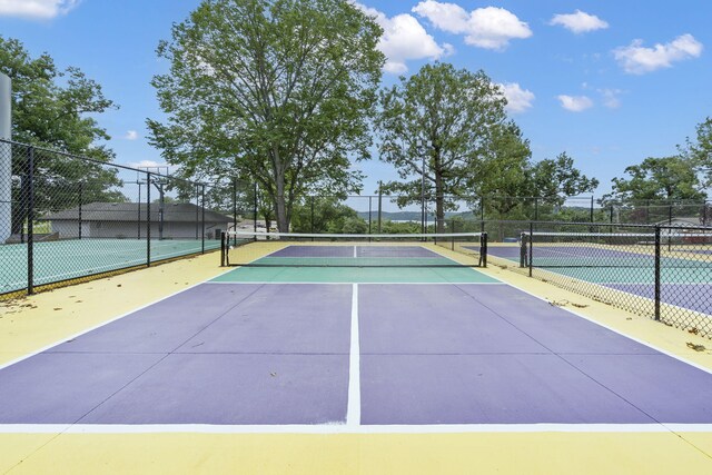 view of tennis court featuring community basketball court and fence