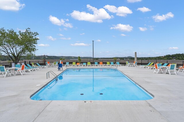 community pool with a patio and fence