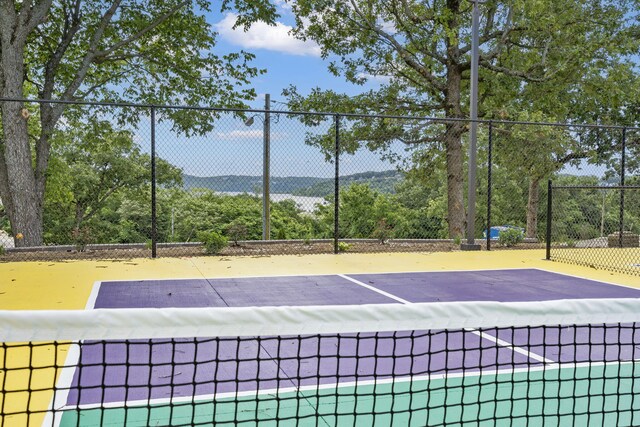 view of tennis court featuring community basketball court and fence