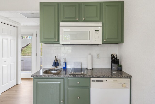 kitchen featuring light wood-type flooring, decorative backsplash, white appliances, and green cabinets