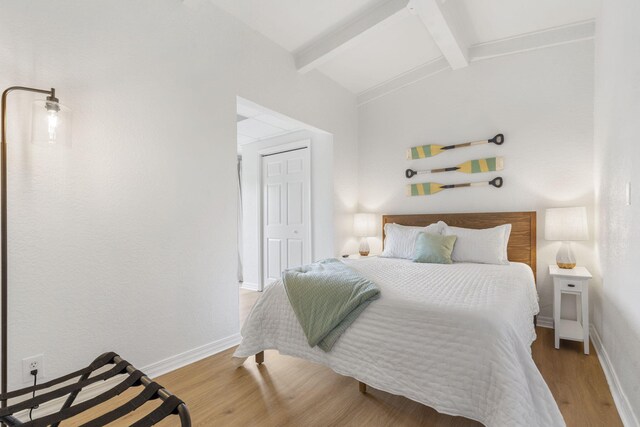 bedroom with vaulted ceiling with beams, wood finished floors, and baseboards