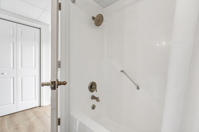 full bathroom with shower / bathing tub combination, wood finished floors, and a paneled ceiling