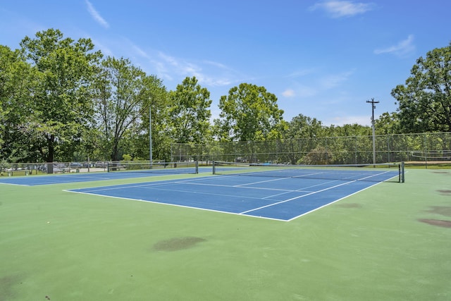 view of tennis court featuring community basketball court and fence