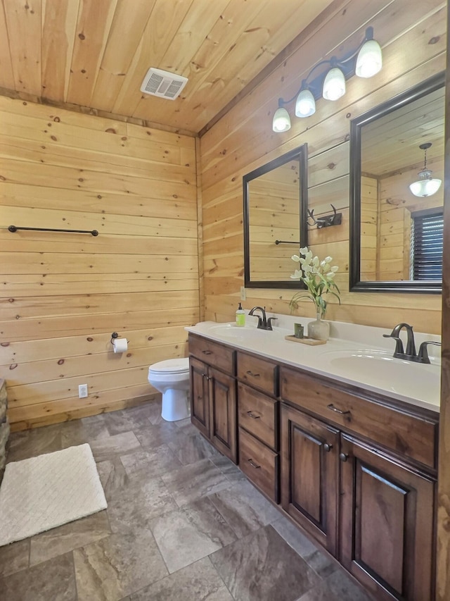 bathroom featuring wood walls, wooden ceiling, vanity, and toilet