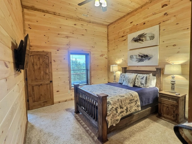 bedroom featuring ceiling fan, wooden walls, and carpet flooring