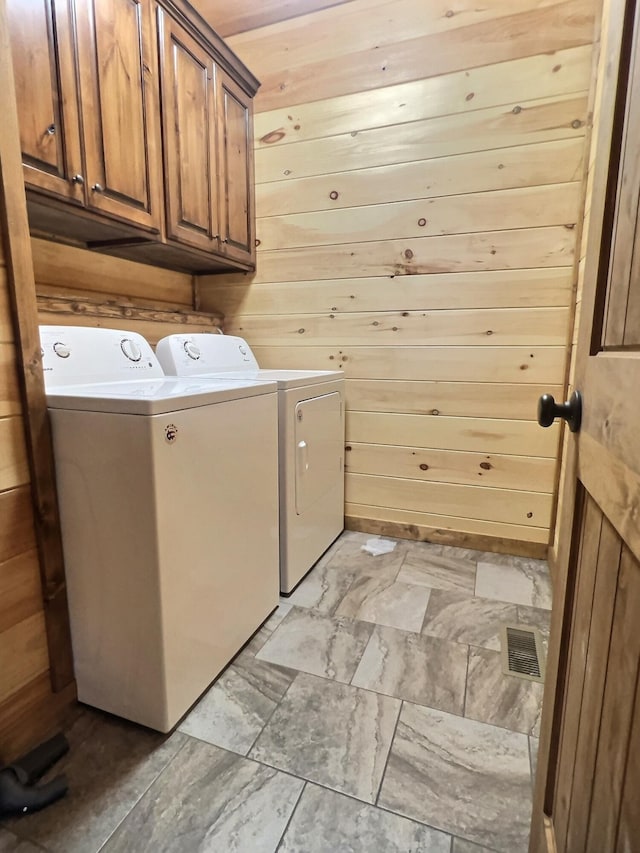 laundry room featuring wood walls, washer and dryer, wood ceiling, and cabinets