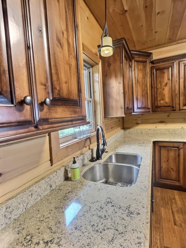 kitchen featuring light stone counters, wood ceiling, hardwood / wood-style flooring, sink, and pendant lighting