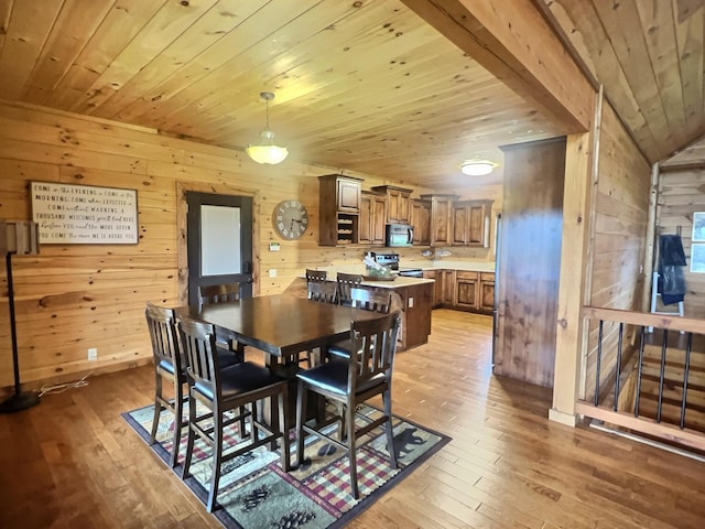 dining room featuring wood ceiling, wooden walls, and light wood-type flooring