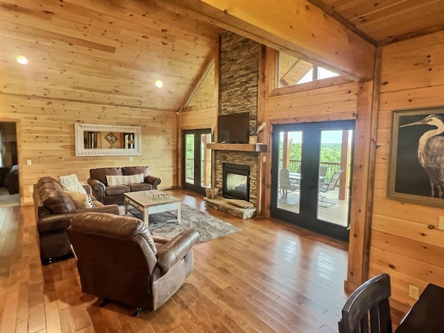 living room featuring light wood-type flooring, wood ceiling, wooden walls, a fireplace, and high vaulted ceiling