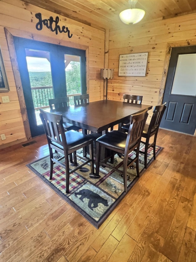 dining space with wood walls, wood ceiling, and wood-type flooring