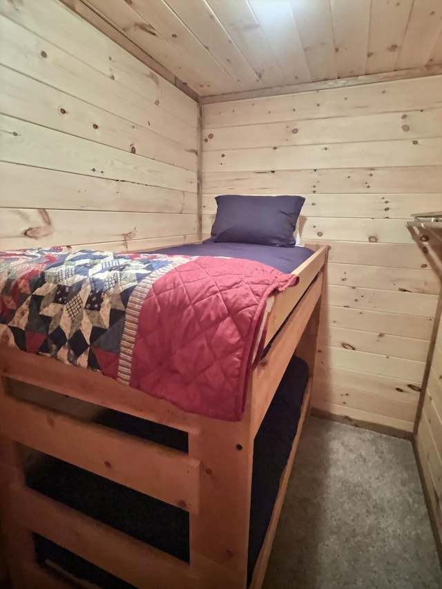 carpeted bedroom featuring wooden walls and wooden ceiling