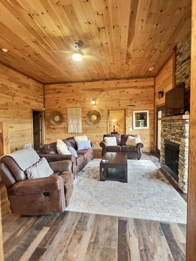 living room with wood-type flooring, a stone fireplace, wooden walls, and wooden ceiling