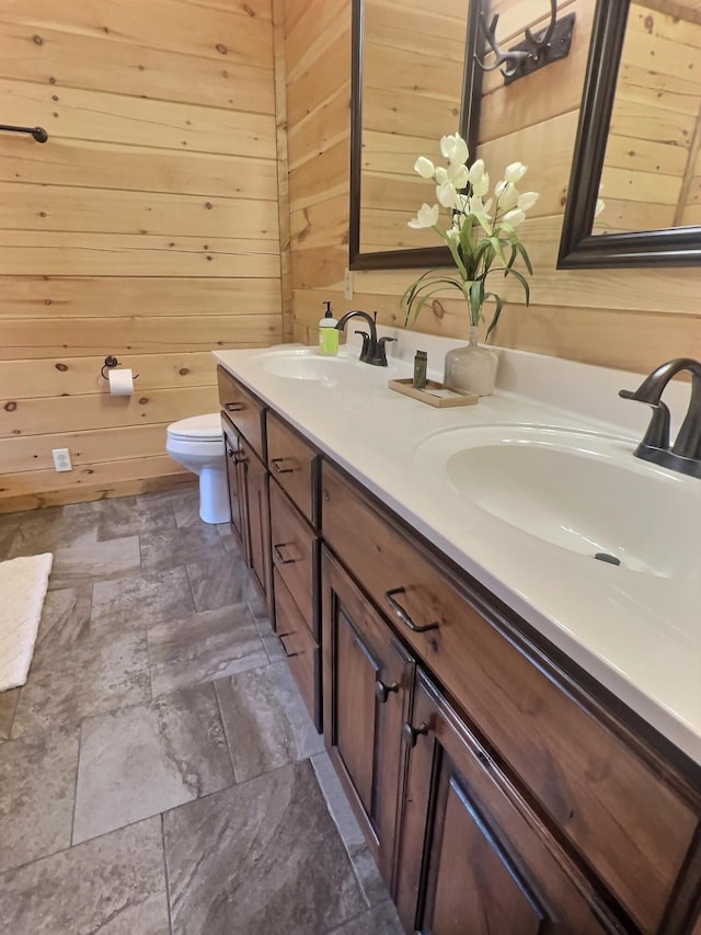 bathroom with wood walls, vanity, and toilet