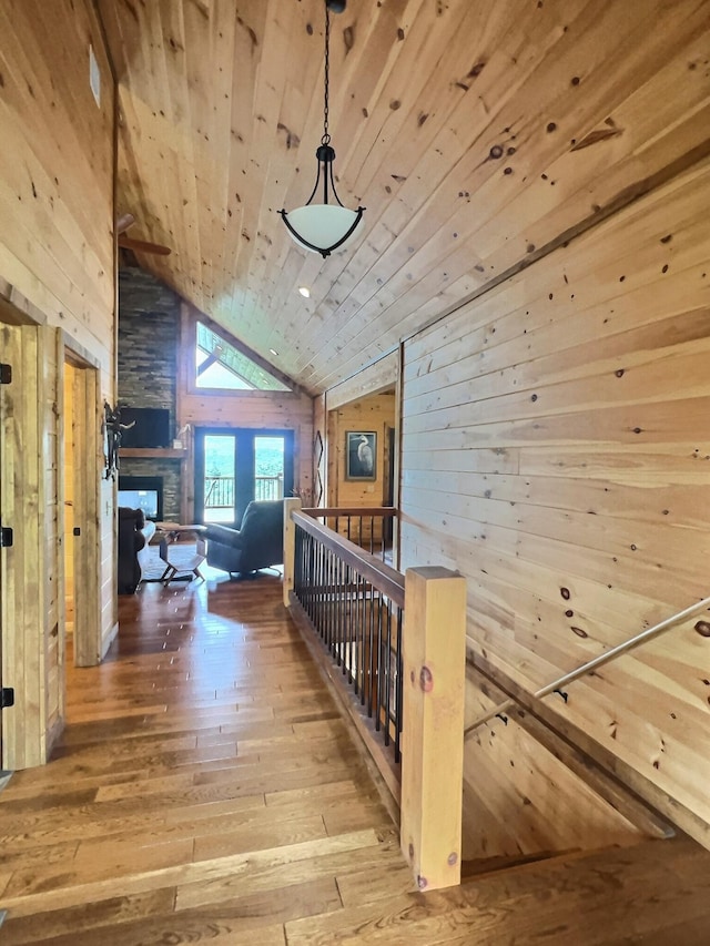 hall with hardwood / wood-style flooring, high vaulted ceiling, wood walls, and wood ceiling