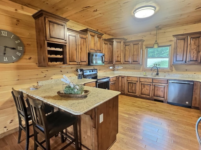 kitchen with light hardwood / wood-style flooring, sink, wooden walls, stainless steel appliances, and light stone countertops