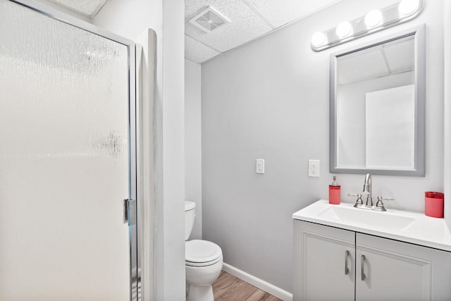 full bathroom with visible vents, toilet, vanity, a paneled ceiling, and a shower stall