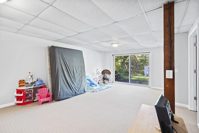 recreation room with a drop ceiling, carpet, and baseboards