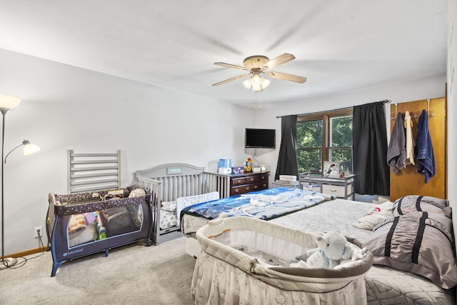 carpeted bedroom with ceiling fan and baseboards