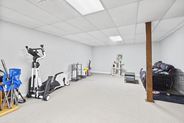 exercise room with a paneled ceiling, carpet flooring, and baseboards