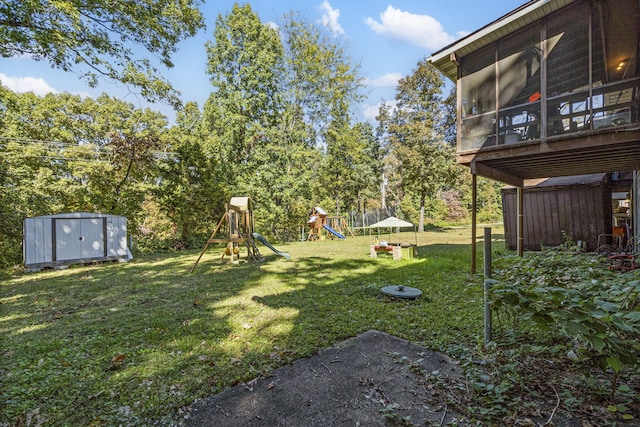 view of yard with a sunroom, a storage unit, a playground, and an outdoor structure