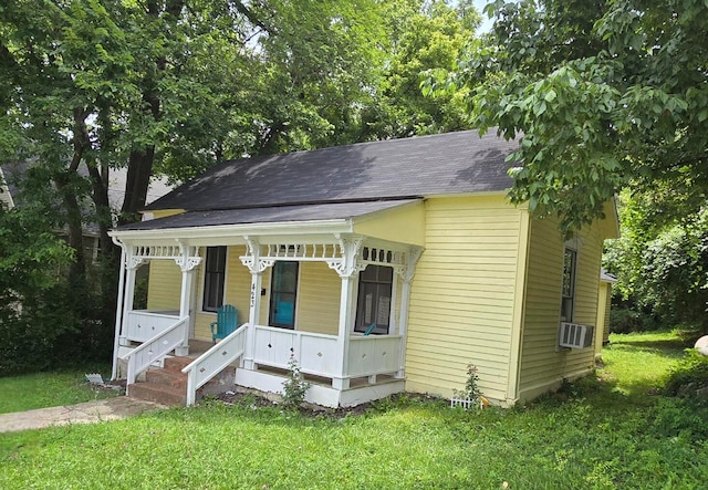 view of front of house featuring cooling unit, a front yard, and covered porch