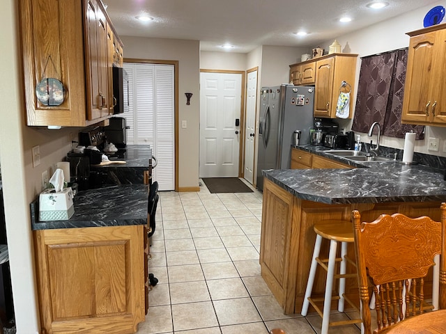 kitchen with stainless steel fridge, sink, kitchen peninsula, a kitchen bar, and light tile patterned floors