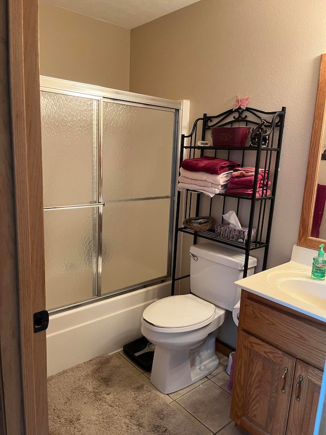 full bathroom featuring shower / bath combination with glass door, toilet, tile patterned flooring, and vanity