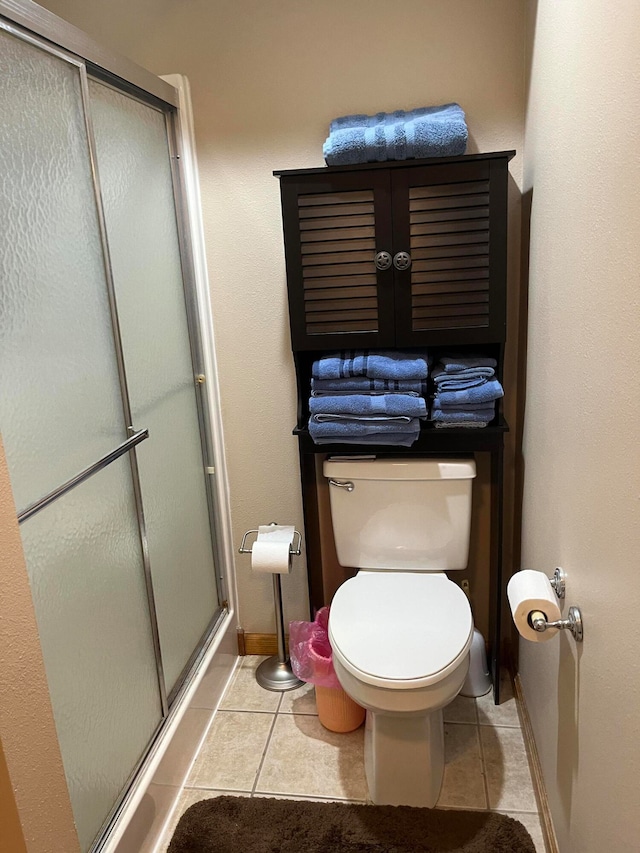 bathroom with an enclosed shower, tile patterned floors, and toilet