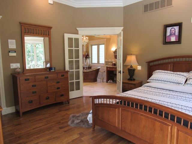 bedroom featuring an inviting chandelier, hardwood / wood-style flooring, french doors, and ornamental molding