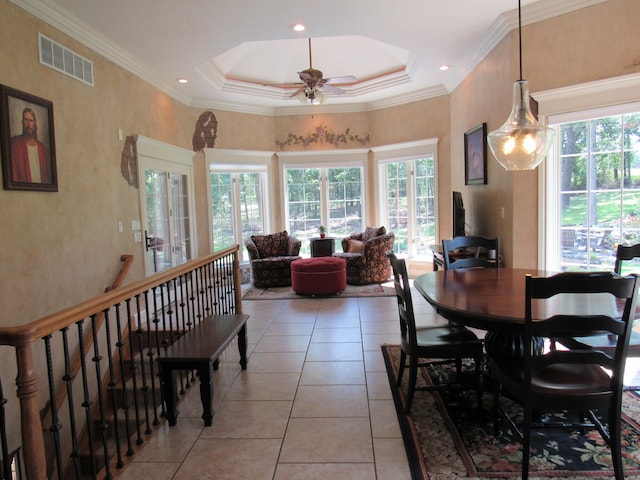 tiled dining space with ceiling fan, a tray ceiling, and crown molding