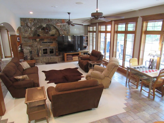 living room with ceiling fan and a stone fireplace