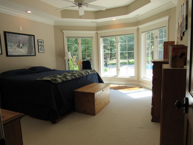 bedroom featuring ceiling fan, a tray ceiling, light carpet, and ornamental molding