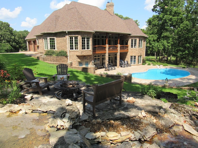 rear view of house featuring a yard, a patio, a fire pit, and a balcony