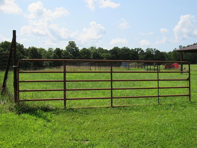 view of gate with a rural view and a lawn