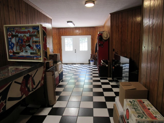 foyer entrance featuring crown molding, wooden walls, and french doors