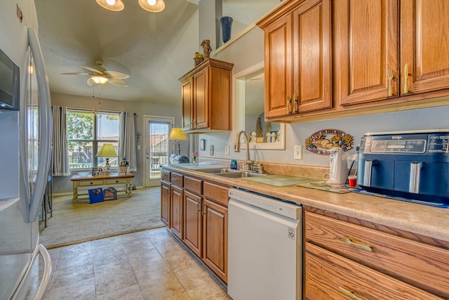 kitchen with dishwasher, a sink, freestanding refrigerator, brown cabinetry, and light colored carpet