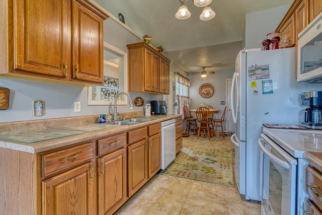 kitchen featuring a sink, a ceiling fan, white appliances, brown cabinets, and light countertops