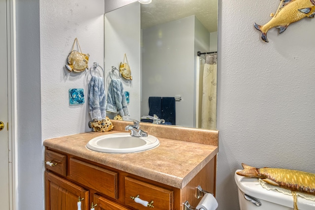bathroom with toilet, a textured wall, and vanity