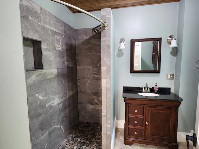 bathroom with a tile shower and vanity