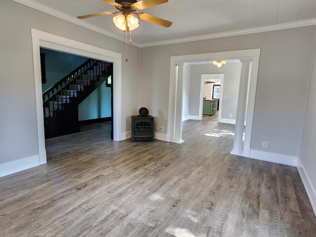 unfurnished living room featuring ceiling fan, ornamental molding, a wood stove, and wood-type flooring