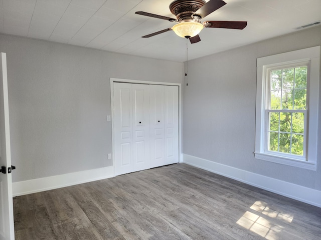 unfurnished bedroom with ceiling fan, a closet, and wood-type flooring