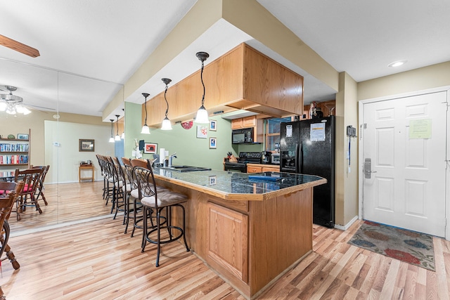 kitchen with pendant lighting, light hardwood / wood-style flooring, and black appliances